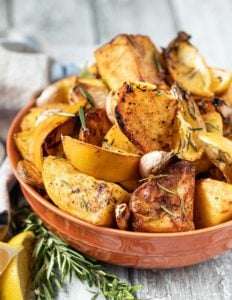 Bowl of roasted potatoes garnished with lemon