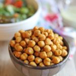 Bowl of chickpeas with salad in the background