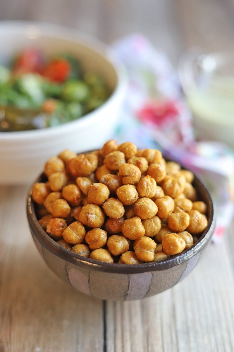 Bowl of chickpeas with salad in the background