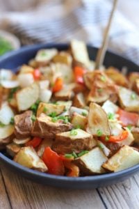 Bowl of potatoes, red bell peppers, and onions garnished with chives