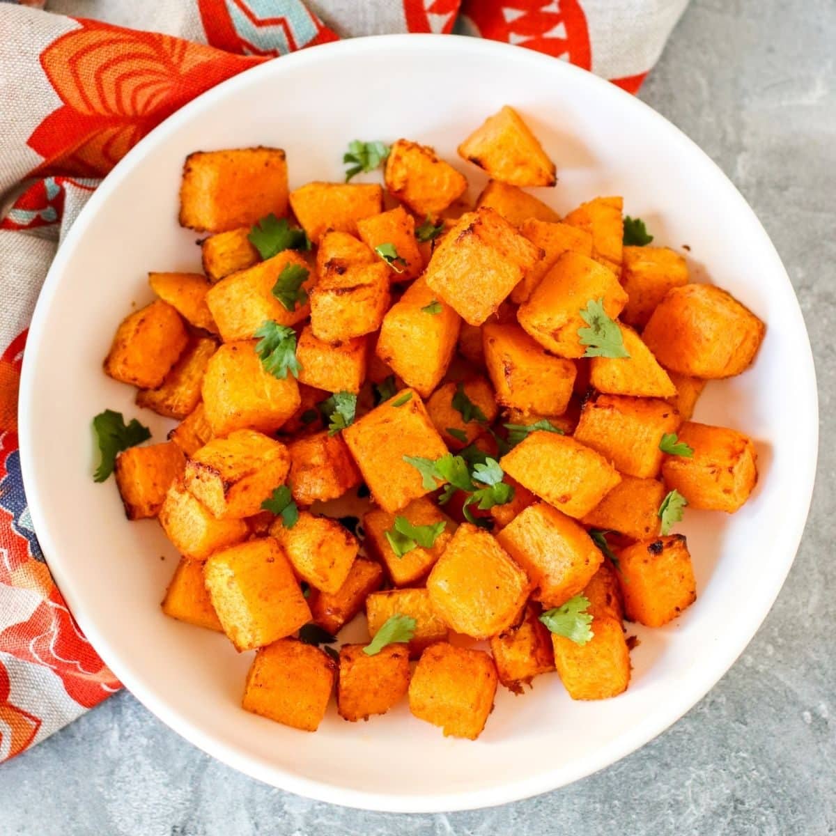 Bowl of butternut squash cubes garnished with fresh cilantro