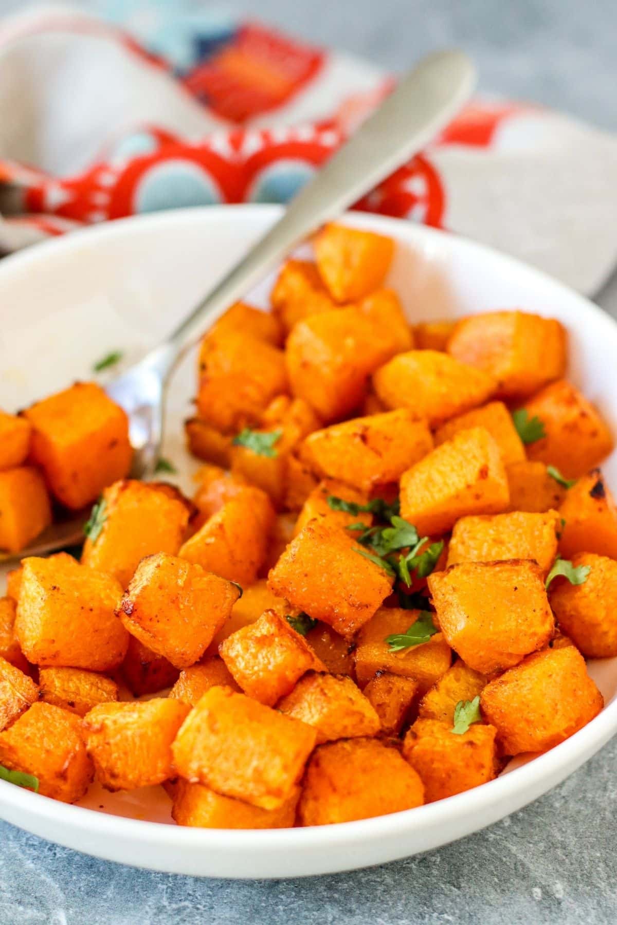 Cooked squash in a bowl with a serving spoon.