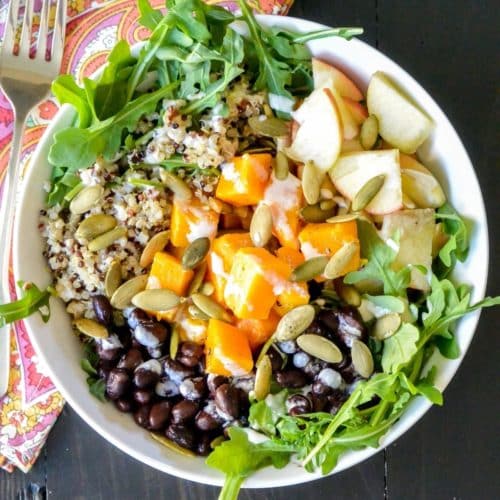 Bowl with arugula, butternut squash, apples, black beans, and quinoa.