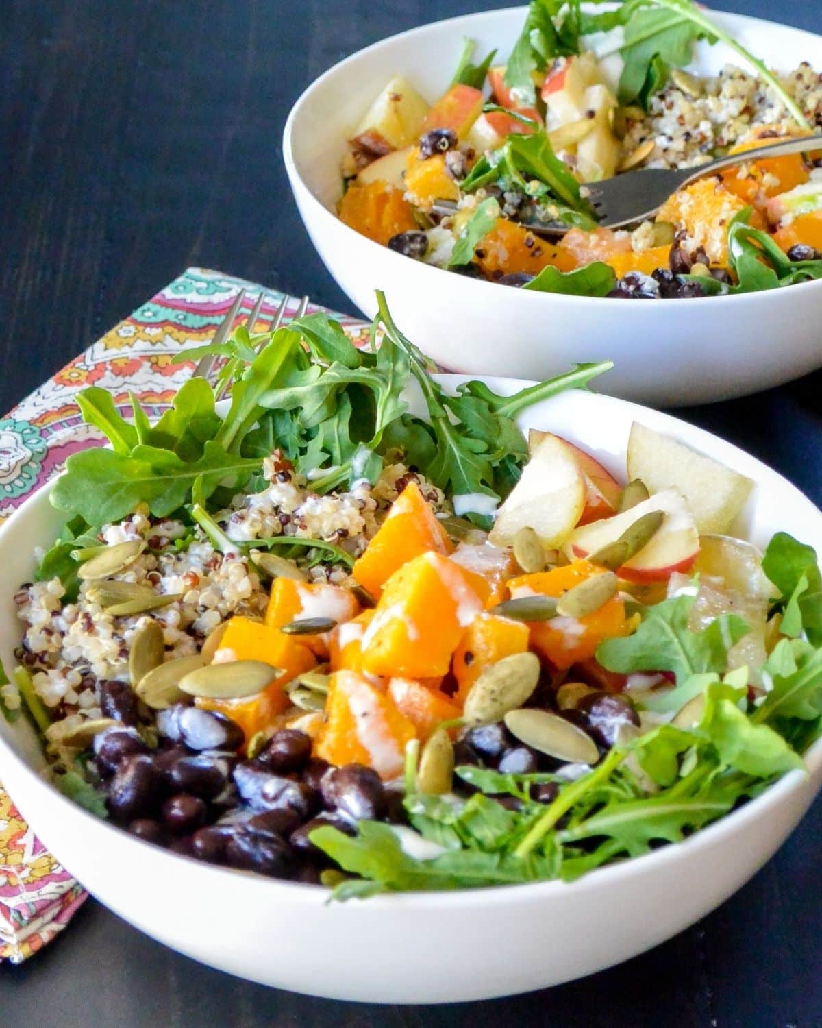 Two quinoa power bowls on a table ready to eat.