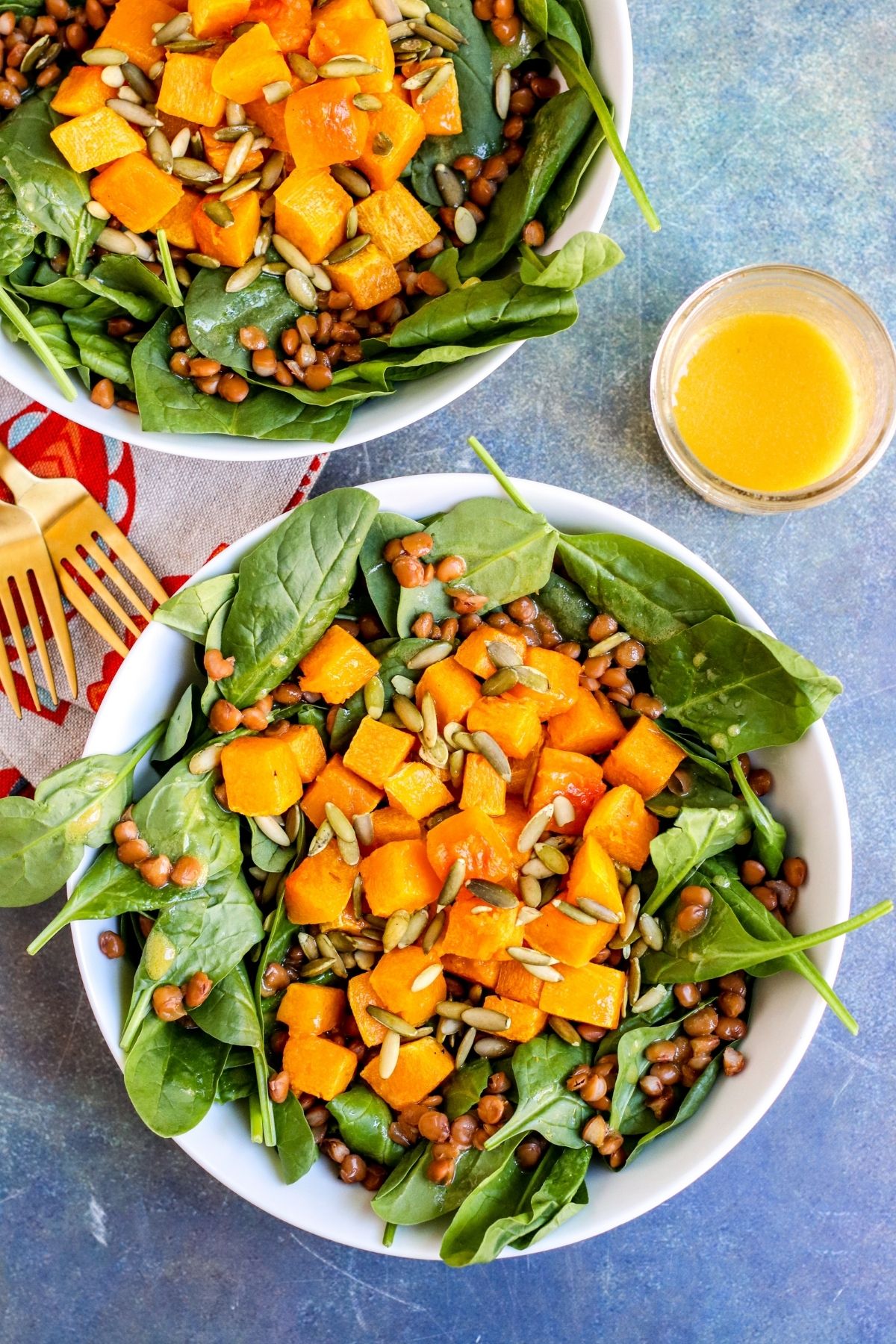 Overhead of 2 salads with jar of dressing.