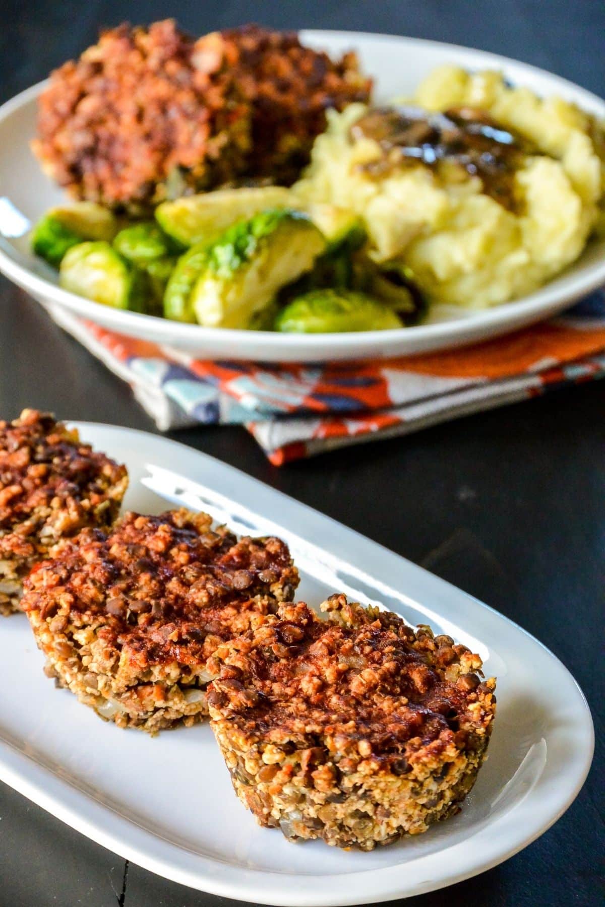 3 meatloaf muffins on a plate with dinner plate in the background.