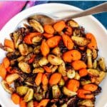 Serving spoon in a bowl of roasted vegetables, with text overlay: Balsamic Roasted Brussels Sprouts and Carrots.