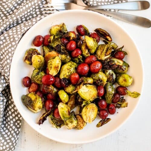 Serving bowl of roasted Brussels sprouts and grapes.