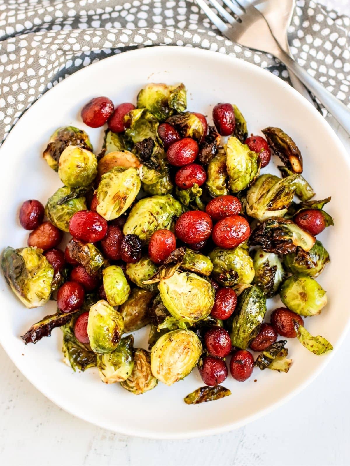 Serving bowl of roasted Brussels sprouts and grapes.