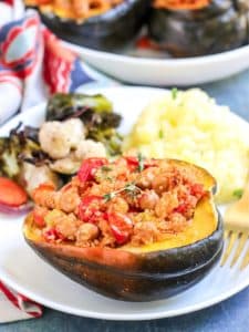 Dinner plate with stuffed acorn squash, roasted vegetables, and mashed potatoes.