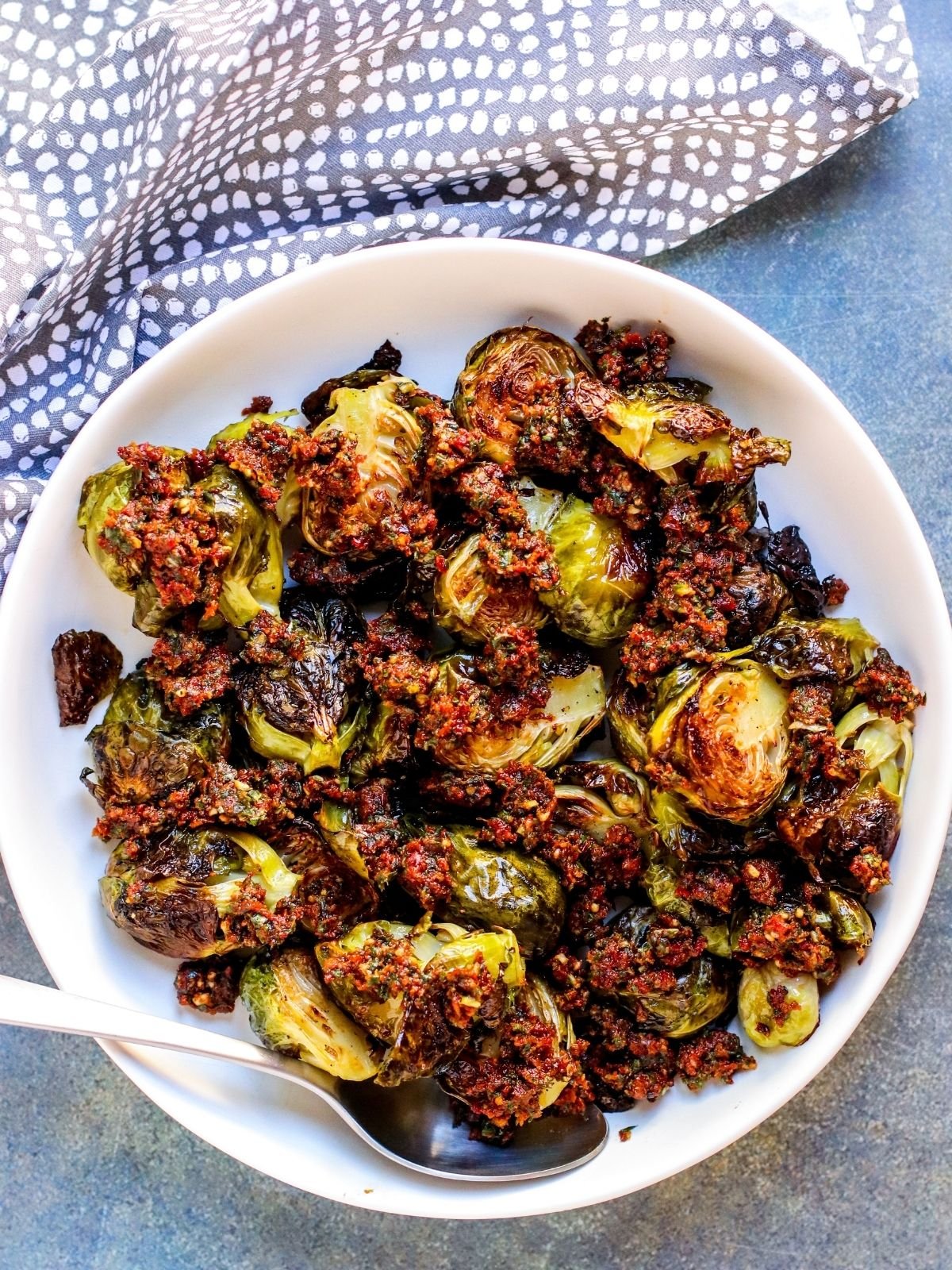 Serving bowl of Brussels sprouts with a spoon in it.