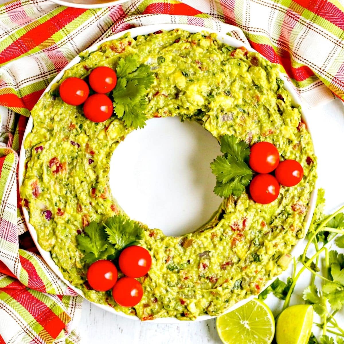 Guacamole garnished with cherry tomatoes and fresh cilantro leaves.