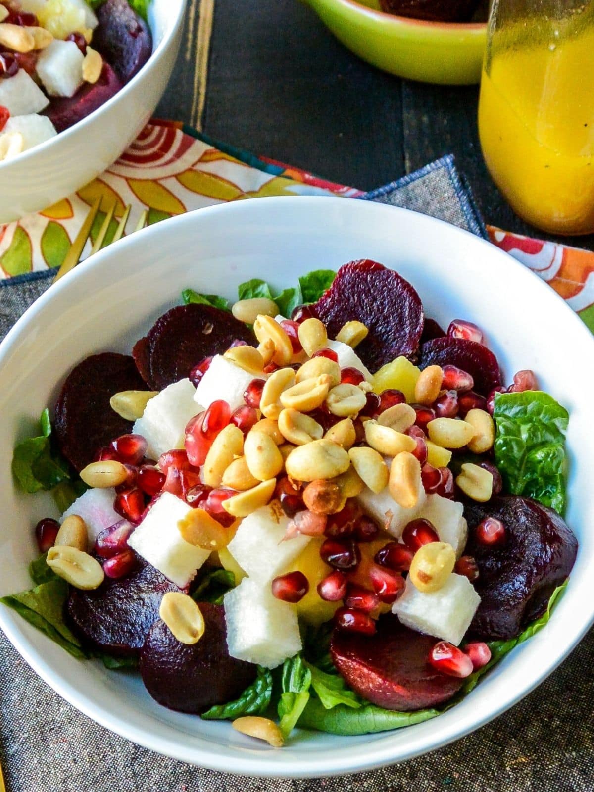 Close up of salad topped with beets, pineapple, jicama, and peanuts.