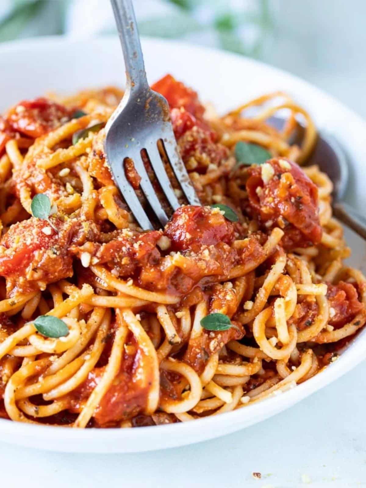 Fork in a bowl of spaghetti with cherry tomato sauce.
