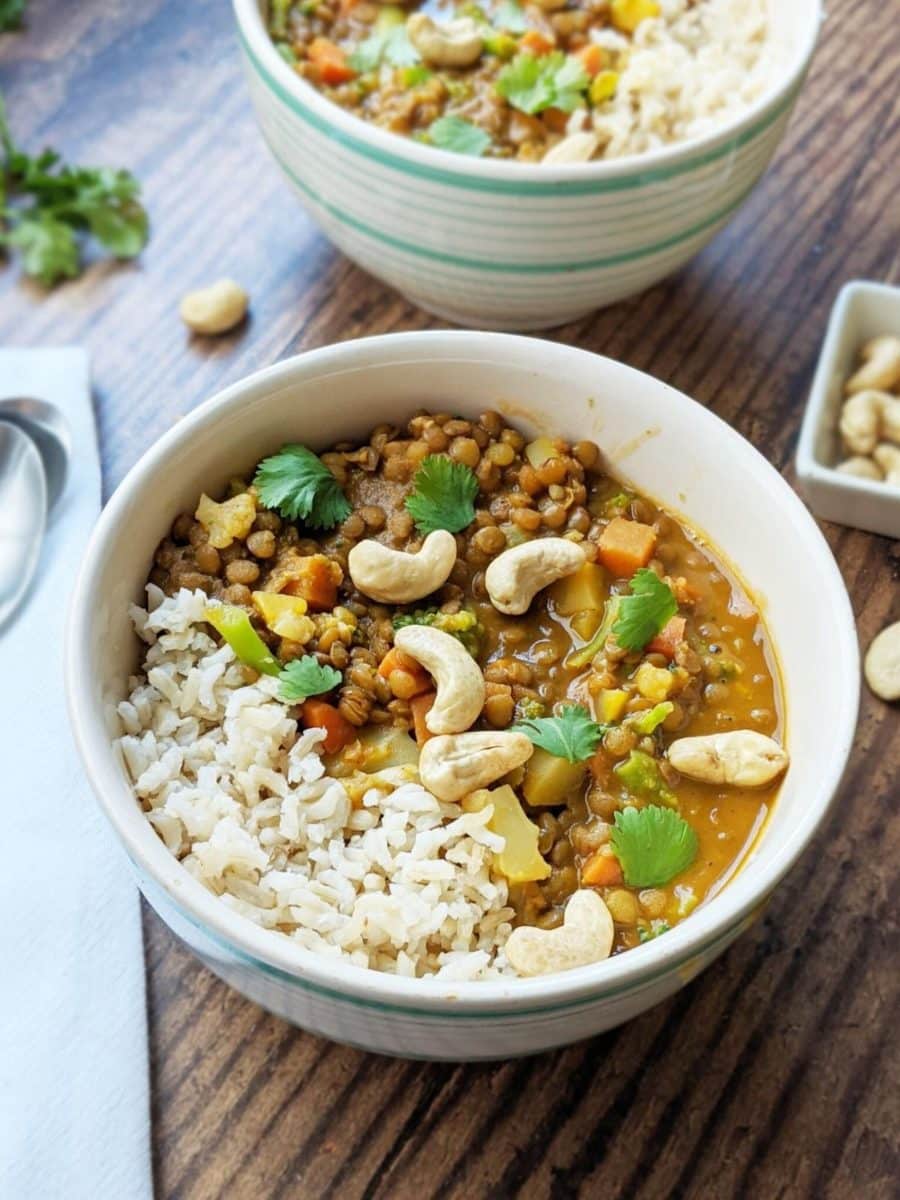 Bowl of rice and lentil curry topped with cashews.