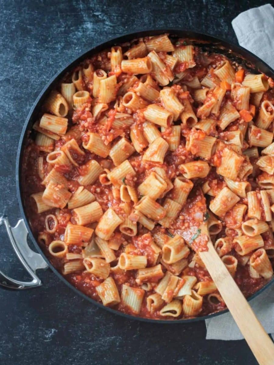 Spoon in a pot of rigatoni with cauliflower bolognese sauce.