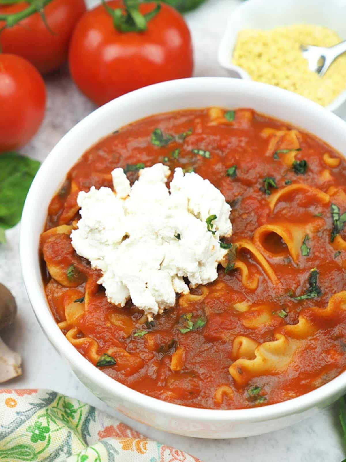 Bowl of lasagna soup topped with a dollop of cashew ricotta cheese.