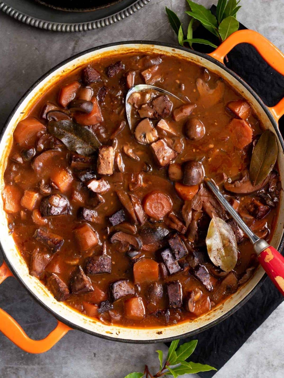 Pot of vegan bourguignon with a spoon in it.