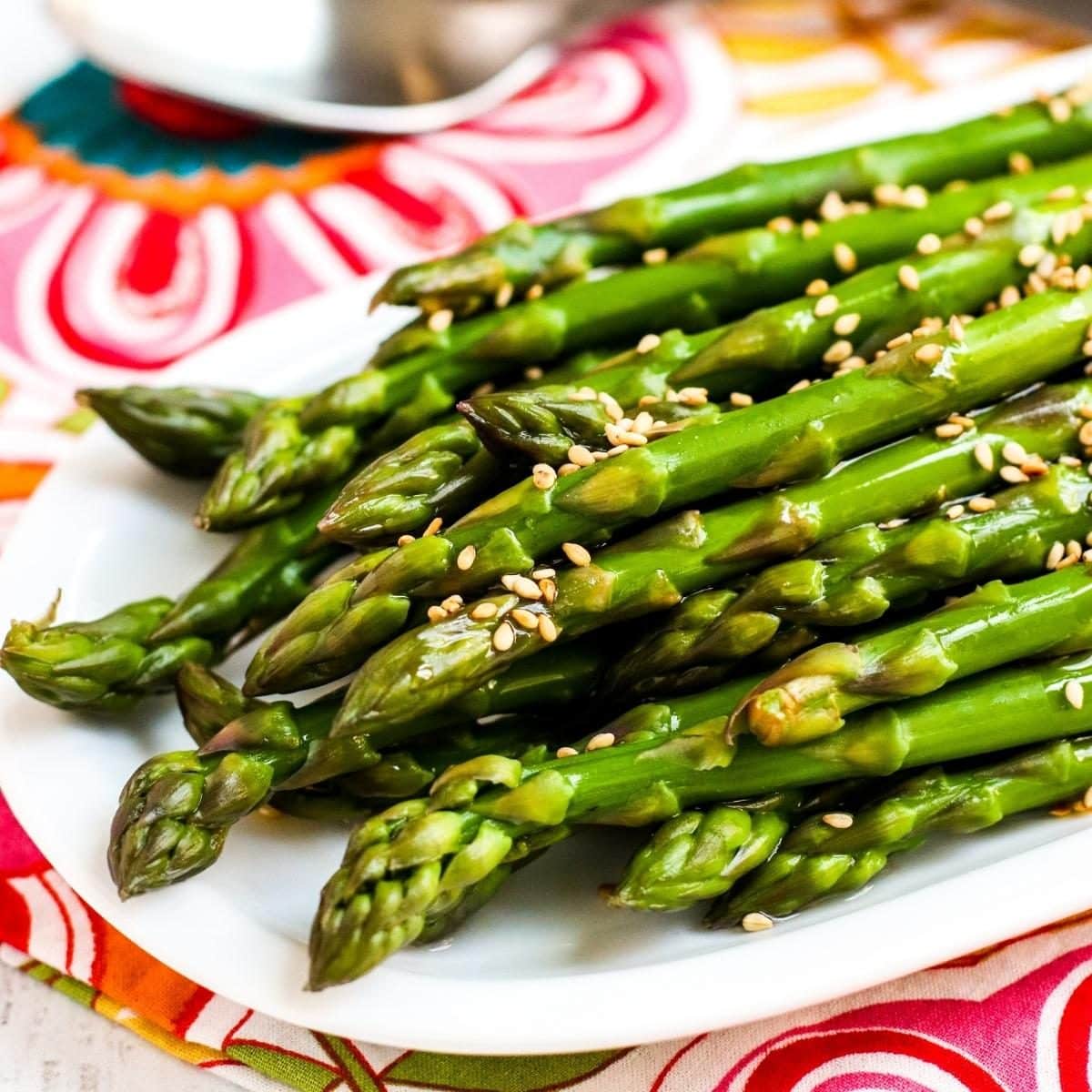 Marinated Asparagus on a platter topped with sesame seeds.