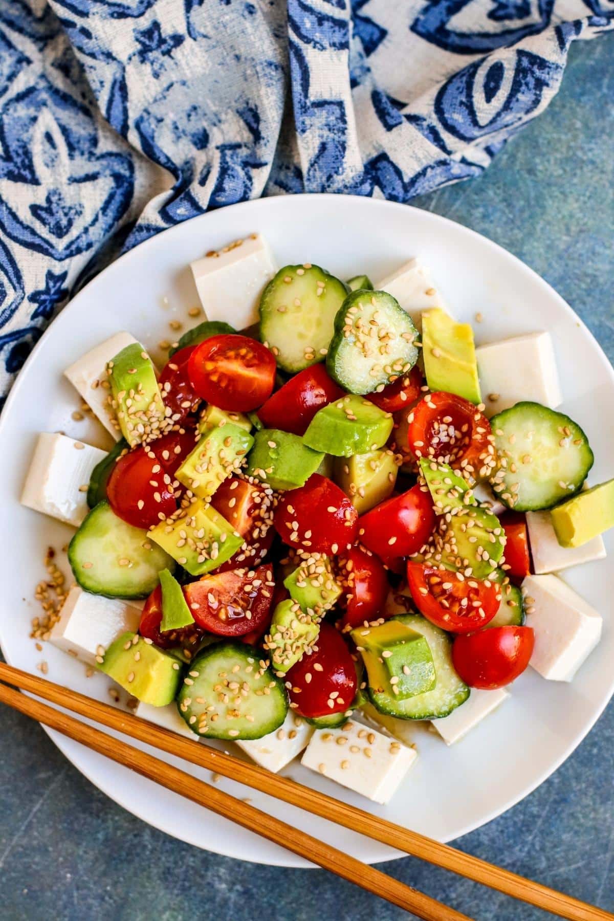 Plate of Silken Tofu Salad with blue napkin and wooden chopsticks.