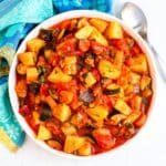 Bowl of zucchini stew with serving spoon.