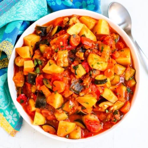 Bowl of zucchini stew with serving spoon.