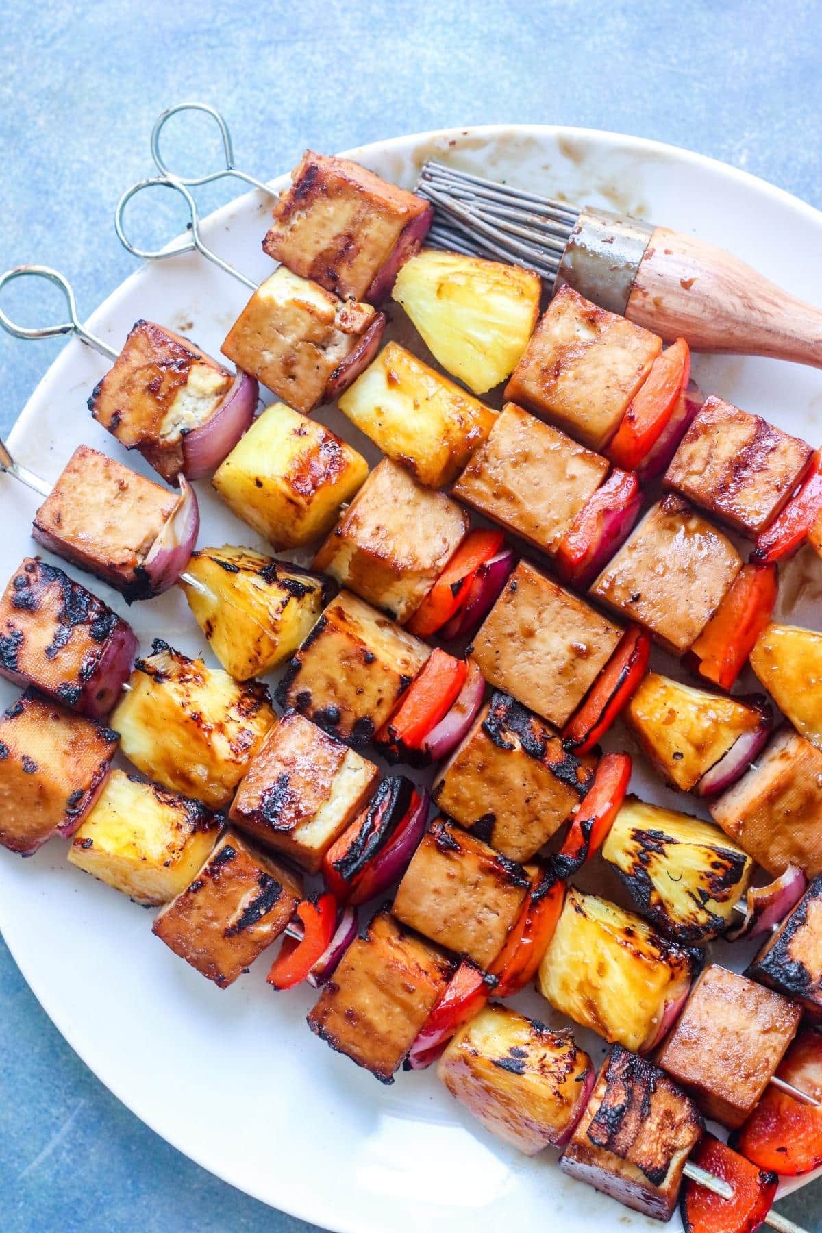 Plate of grilled tofu skewers with silicone basting brush.