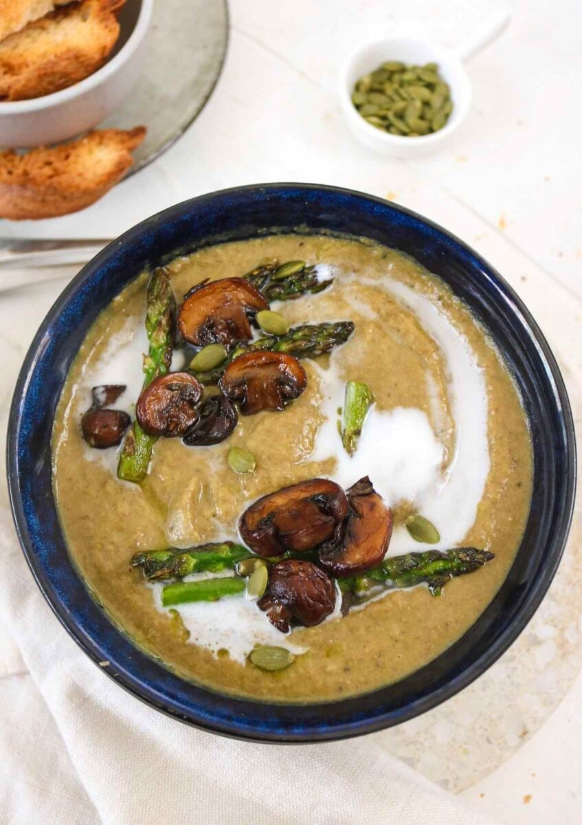 Bowl of Asparagus Mushroom Soup garnished with asparagus spears and sauteed mushrooms.