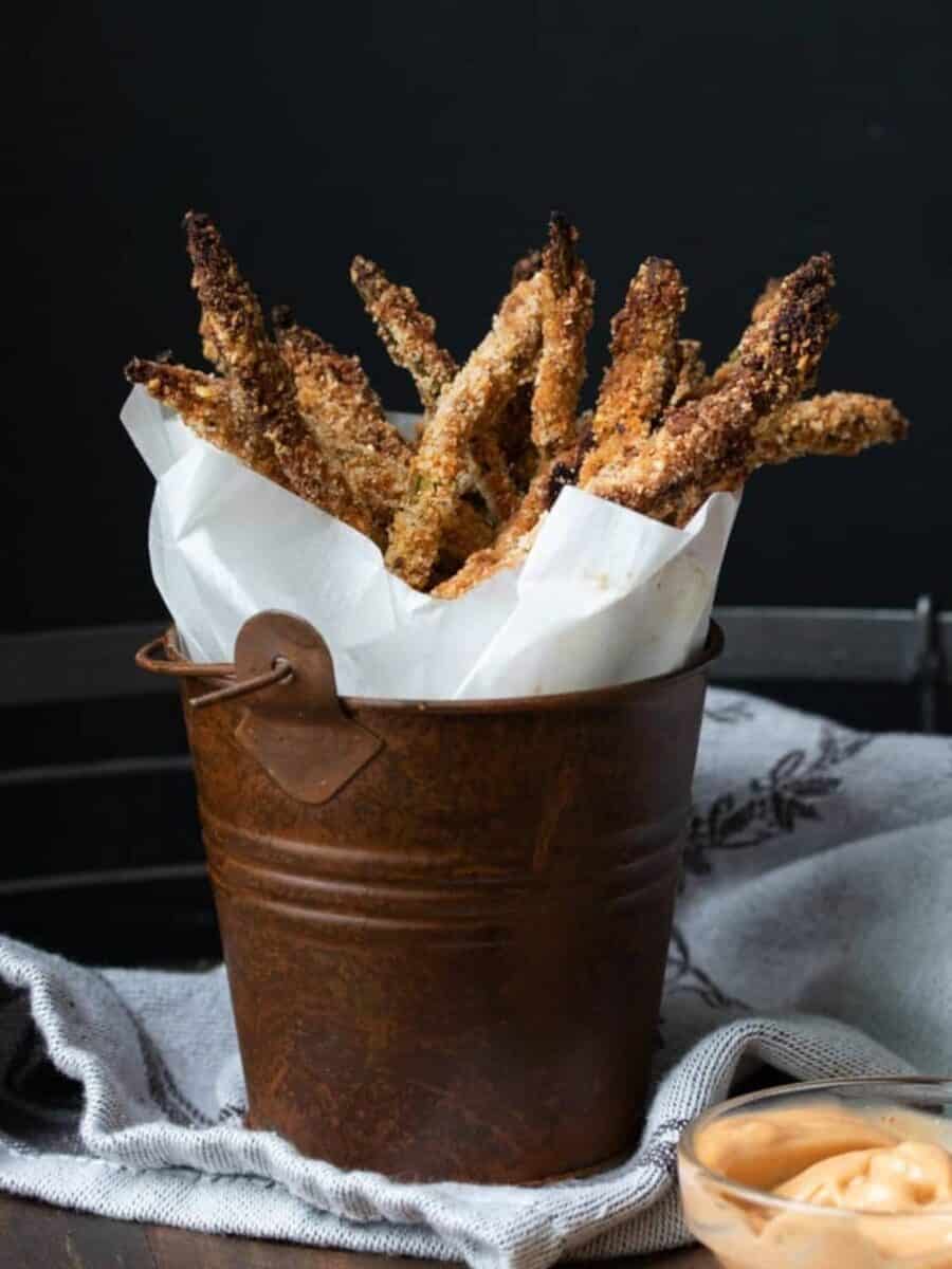 Basket of baked asparagus fries with a side of dipping sauce.