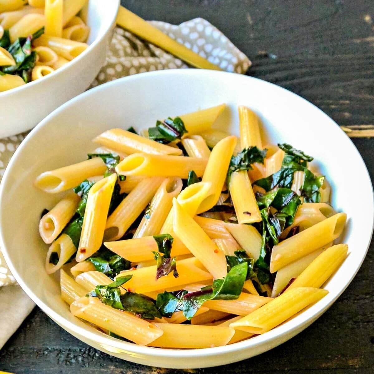 Bowl of penne with sauteed swiss chard.