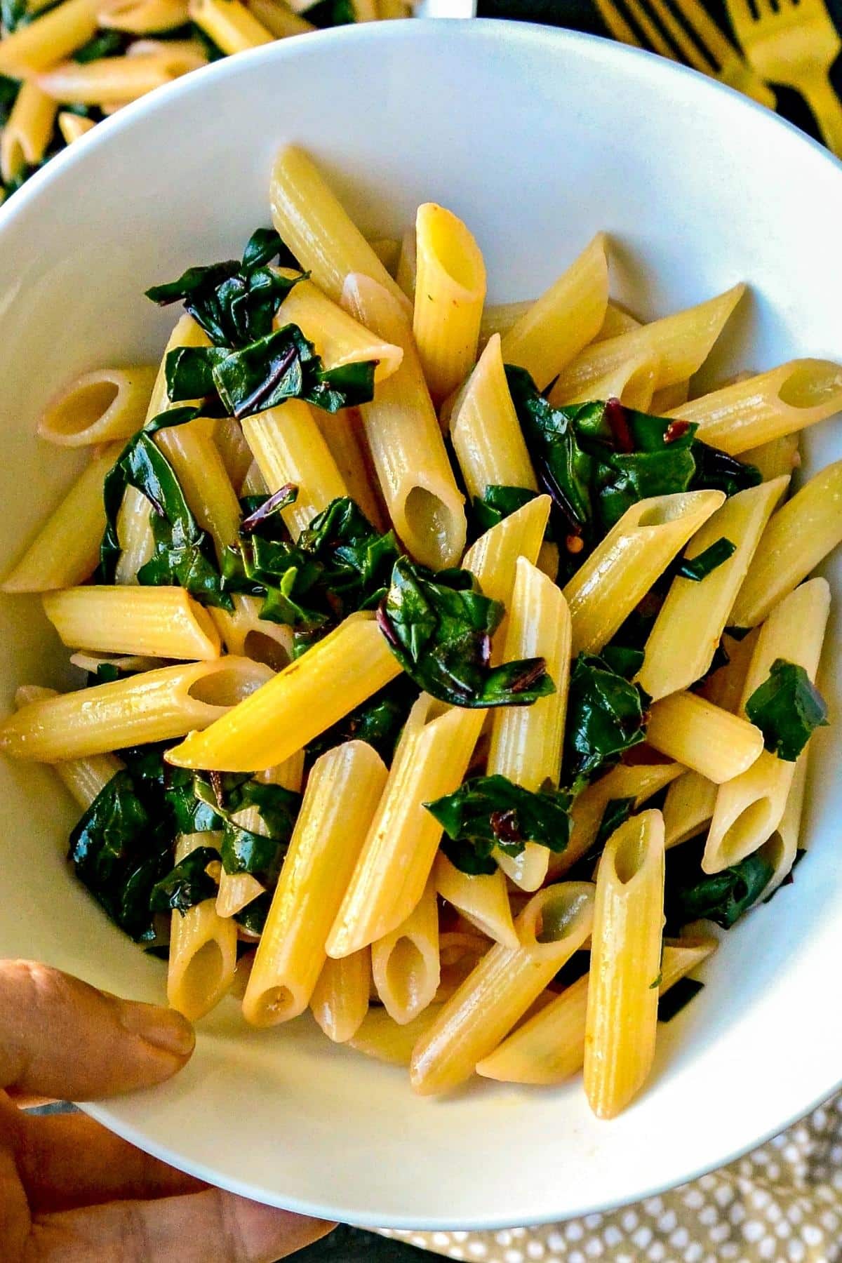 Hand holding a bowl of pasta.