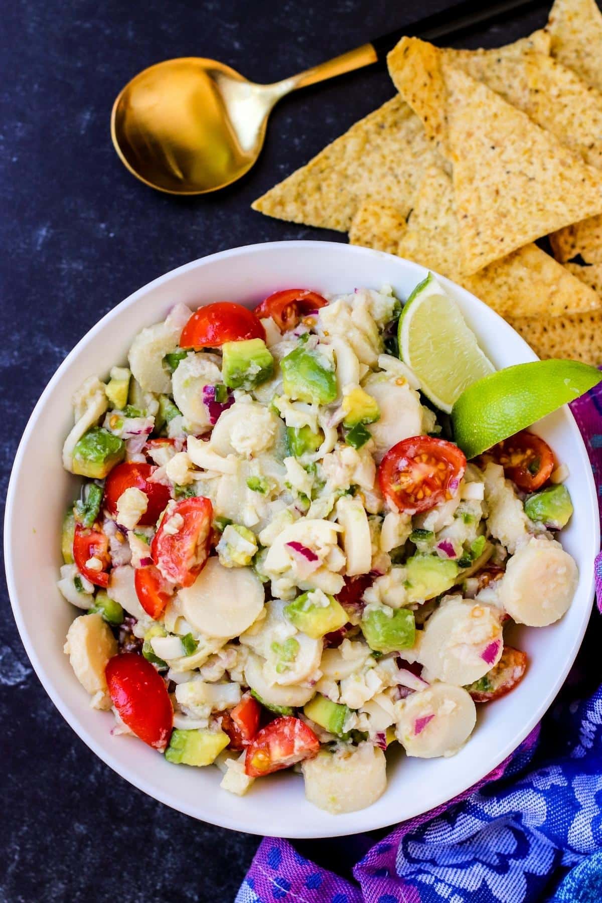 Bowl of Hearts of Palm Ceviche with gold spoon and tortilla chips next to it.