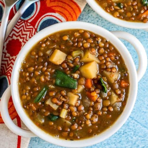 Bowl of lentil soup with orange and blue floral napkin.