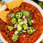 Bowl of chili garnished with jalapeno peppers, red onions, and cilantro with tortilla chips on the side with text overlay Instant Pot Vegan Chili.
