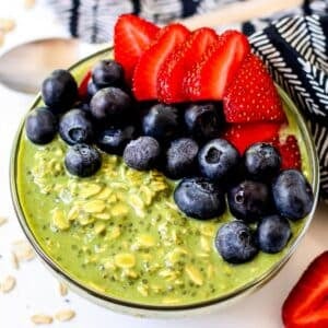 Bowl of Matcha Overnight Oats topped with fresh blueberries and sliced strawberries.