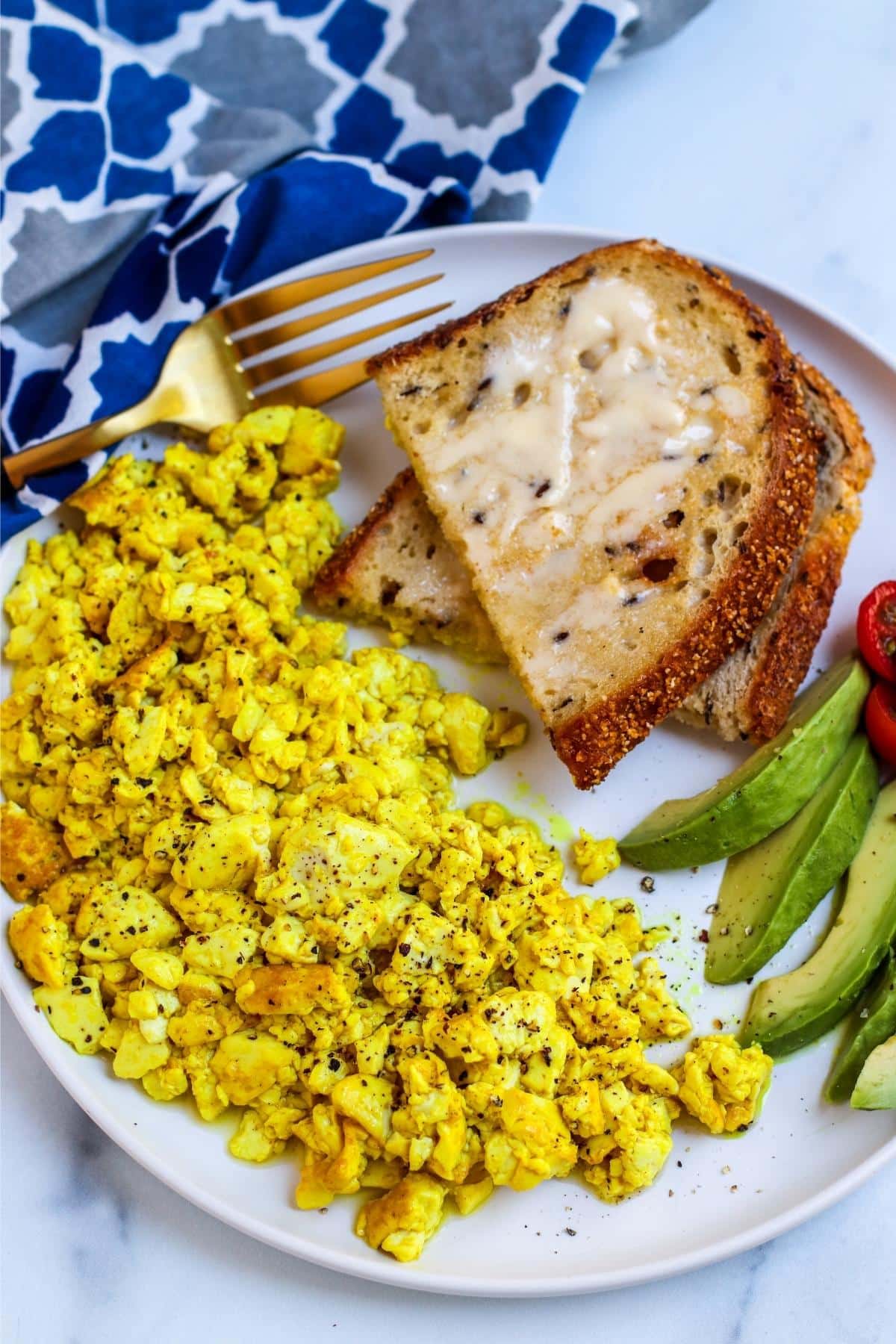 Close up image of the scrambled tofu on a plate with toast and avocado slices.