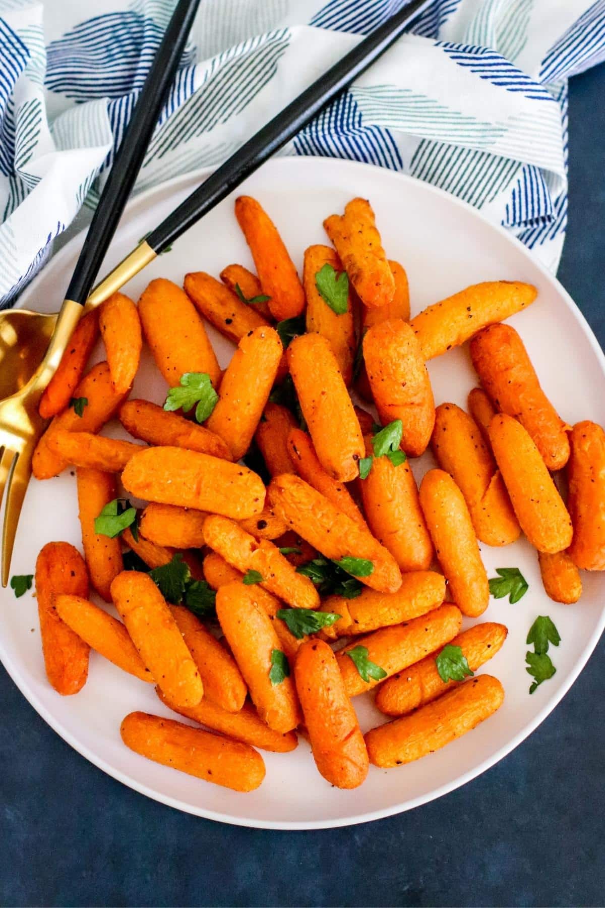 Plate of air fryer baby carrots garnished with fresh parsley.