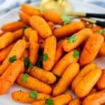 Plate of carrots garnished with fresh parsley, with text overlay: Air Fryer Baby Carrots.