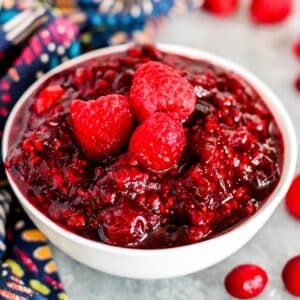 Bowl of cranberry sauce garnished with fresh raspberries.