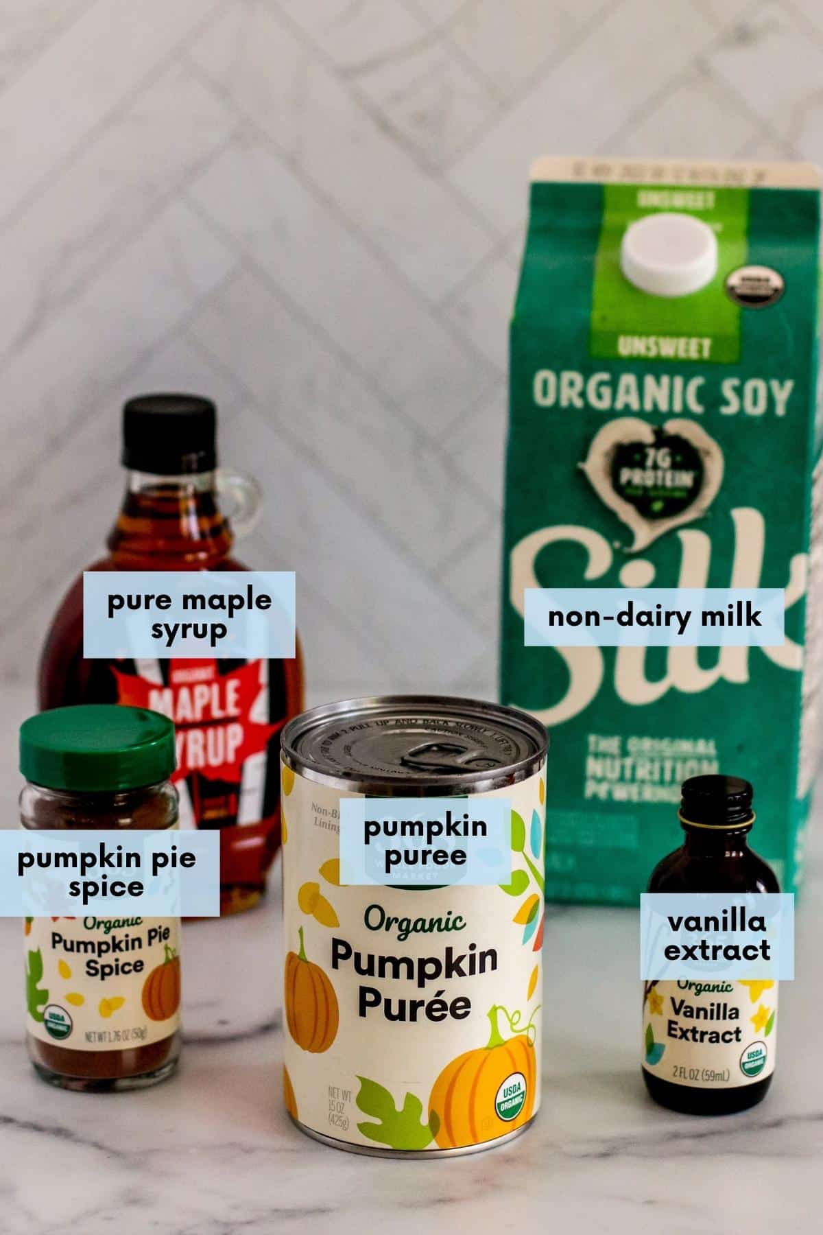Labeled ingredients: Bottle of pure maple syrup, carton of non-dairy milk, bottle of pumpkin pie spice, can of pumpkin puree, and bottle of vanilla extract.