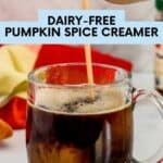 Pumpkin spice creamer being poured into a clear glass mug of black coffee.