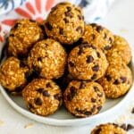 Plate of pumpkin balls and one in front of the plate with a bite taken out of it.