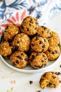 Plate of pumpkin balls and one in front of the plate with a bite taken out of it.