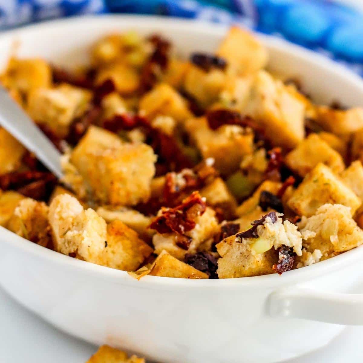 Stuffing in a casserole dish with a serving spoon.