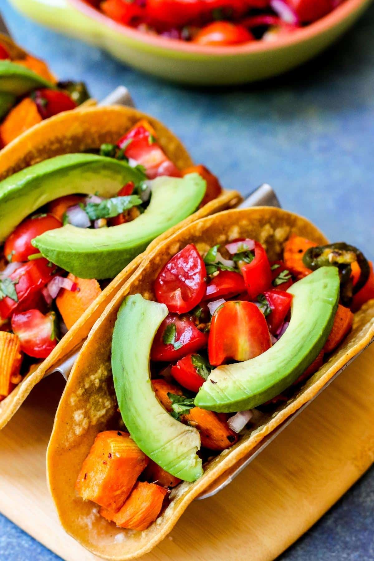 Corn tortillas filled with roasted sweet potatoes, pico de gallo, and avocado slices.