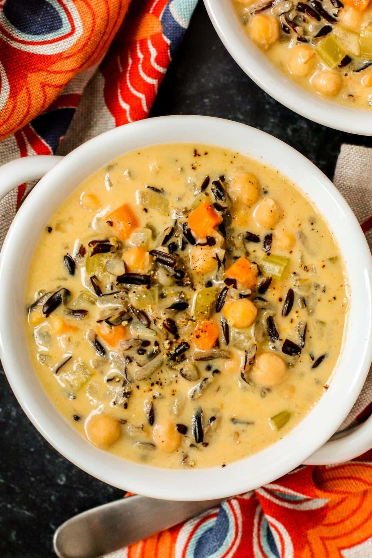 Bowls of vegan wild rice soup with orange and blue floral napkins.