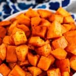Bite-sized pieces of crispy roasted sweet potatoes with text overlay: Seasoned Roasted Sweet Potato Cubes.