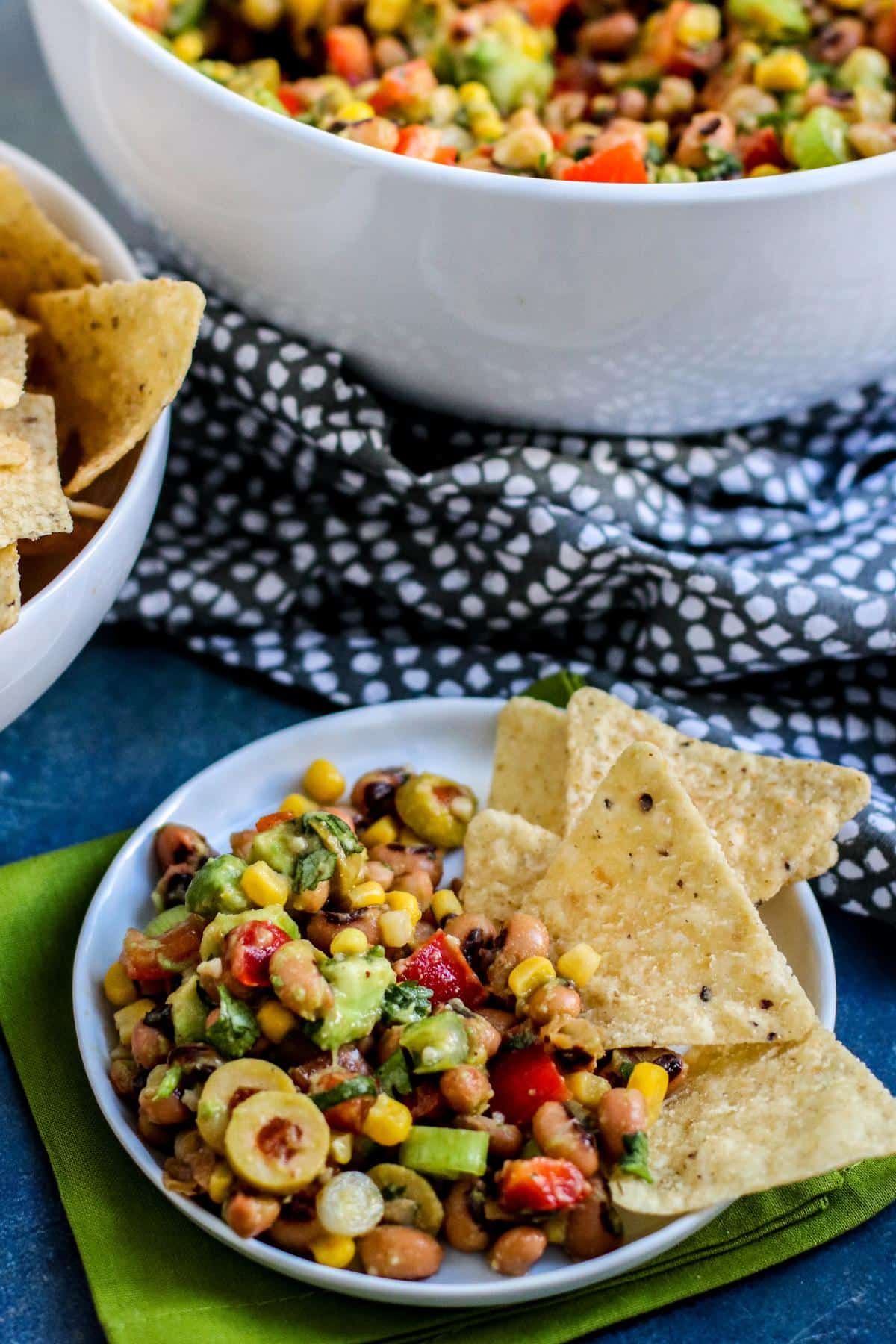 Small plate of black eyed pea dip with tortilla chips on the side.