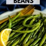 Plate of green beans with a wedge of lemon and text overlay Air Fryer Green Beans.