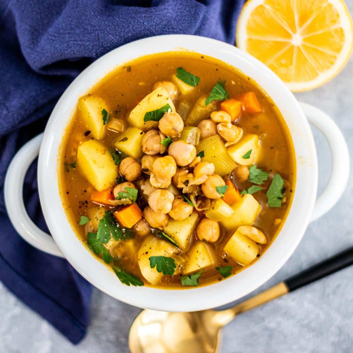 Bowl of soup with lemon and spoon next to it.